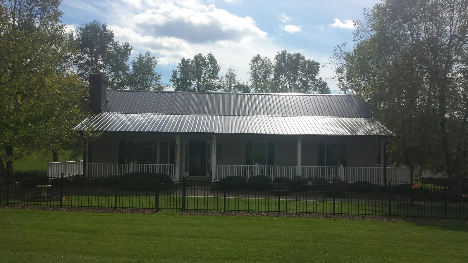 Gray metal roof on a brick ranch with a full width front porch — Gutter Guard Installation work by our crew in Belmont