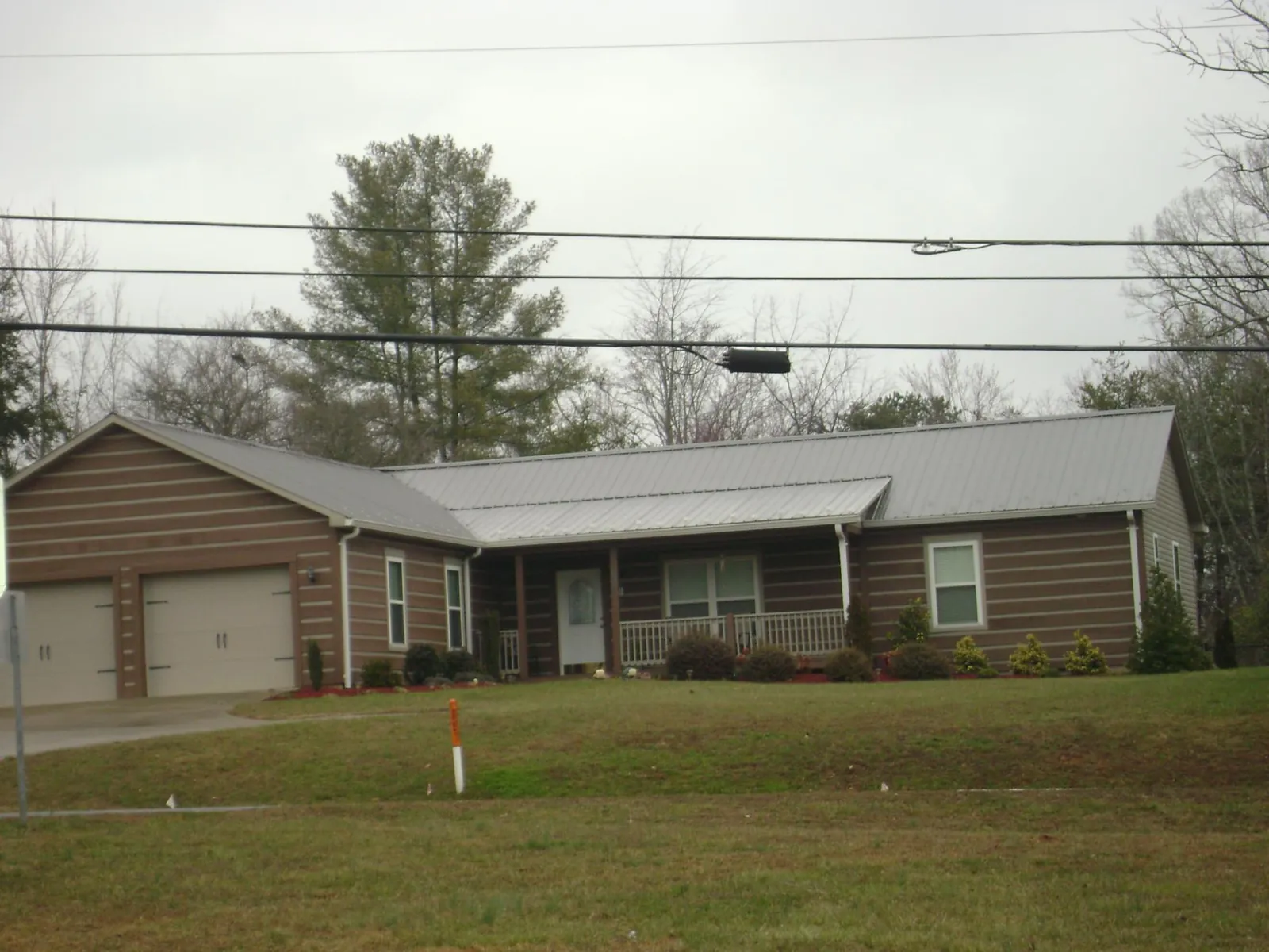 Gray metal roof on a log sided ranch home with a front porch in Belmont